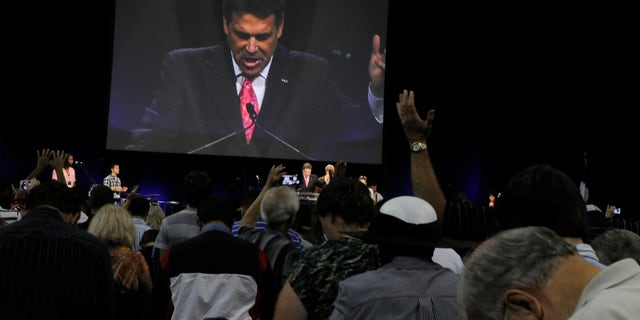Worshippers pray with Texas Gov. Rick Perry, seen at center and on screen, at The Response, a day long prayer and fast rally, Saturday, Aug. 6, 2011, at Reliant Stadium in Houston.