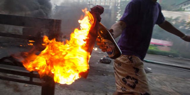 BANGKOK, THAILAND - MAY 16: An anti-government protester 'Red Shirt' throws a molotov cocktail toward Thai security forces as the violence in central Bangkok continues on May 16, 2010 in Bangkok, Thailand. So far at least 154 have been injured and over 20 killed in the clashes as the military and the government launched an operation to disperse anti-government protesters who have closed parts of the city for two months. A state of emergency is in effect that spreads to 17 provinces in the country. The Thai army declared certain protest areas where clashes are taking place as a "Live Fire Zone." (Photo by Athit Perawongmetha/Getty Images)