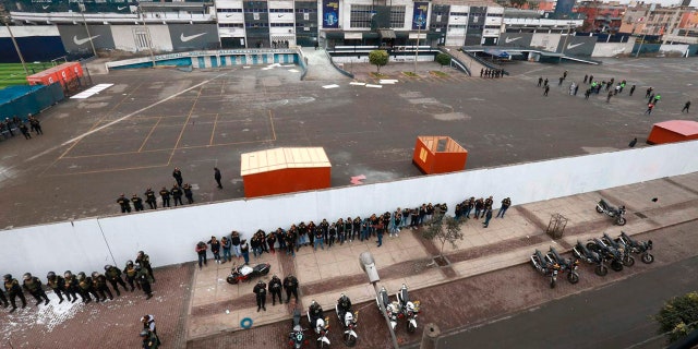 In this photo provided by the Andina government news agency, police stand guard outside the parking lot of the Alianza Lima soccer club stadium after clashes between the club's fans and members of an evangelical church in Lima, Peru.