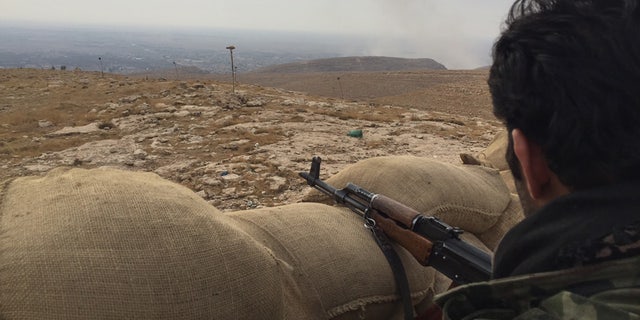 A Kurdish Peshmerga fighter takes position overlooking the town of Bashiqa, Iraq.