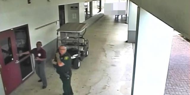 Former Deputy Scot Peterson, right, is seen on video taken during the Feb. 14 Florida school shooting.