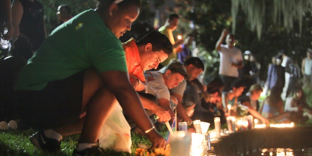 Wendy Frias, from left, and Hector Silva light candles along Lake Eola in Orlando, Sunday, June 12, 2016. The New York natives have made Orlando their home in recent years and came to the vigil for the victims of the Pulse night club tragedy.