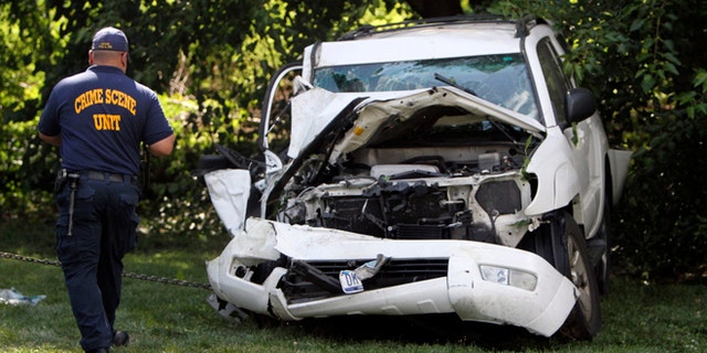 July 25, 2014: An investigator examines a heavily damaged SUV before it is towed from the scene of a fatal accident in North Philadelphia.