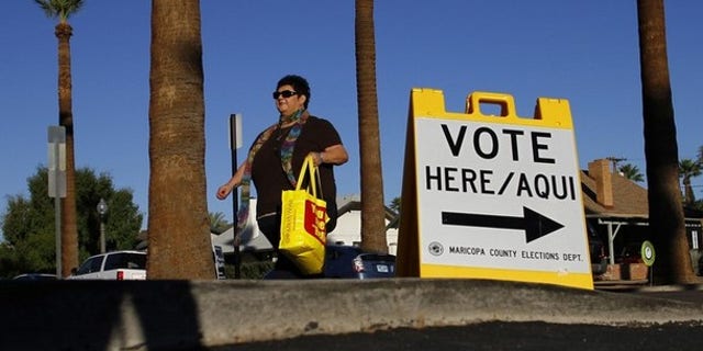 A woman walks past a sign directing voters to a polling place in the Phoenix, Ariz., Nov. 2, 2010.