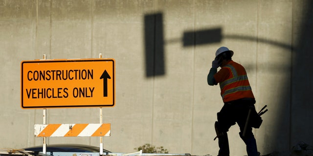 A worker talks on a mobile phone from a downtown construction site in Los Angeles, Calif. Jan. 29, 2016. (REUTERS/Mike Blake)