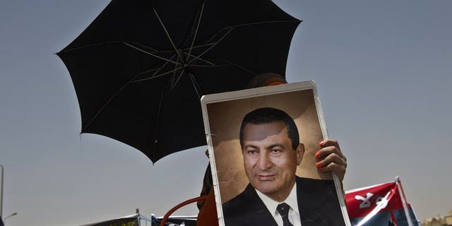 A supporter of Hosni Mubarak holds a portrait of him outside the court in Cairo last week during his retrial. An Egyptian court on Tuesday ended Mubarak's detention in one corruption case, judicial sources told AFP, but the ousted president will remain in custody on other charges.