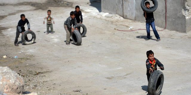Syrian children roll used car tyres on a street in the northern Syrian city of Aleppo on April 12, 2013. An epidemic of measles is sweeping through parts of northern Syria, with at least 7,000 people affected because the ongoing civil war has disrupted vaccination programmes, Doctors Without Borders said on Tuesday.