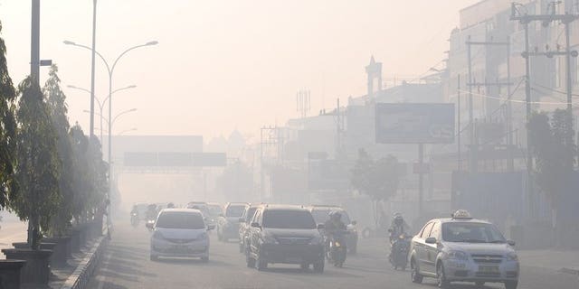 Commuters travel on a road blanketed by haze due to nearby forest fires, in Pekanbaru city, capital of Riau province on Sumatra island on June 19, 2013. Indonesia plans to use weather changing technology to try to unleash torrents of rain and extinguish raging fires on Sumatra island that have cloaked neighbouring Singapore in thick haze, an official said Wednesday.