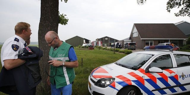 Policemen and rescue workers stand in front of a farm in Makkinga in northern Netherlands, where three men were killed and on man injured after an accident in a manure silo on June 19, 2013. Three farmworkers died after falling into a manure silo in the northern Netherlands, with a survivor flown to hospital in a critical condition