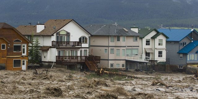 Damaged houses along the edge of floodwaters in Cougar Creek in Canmore, Alberta, western Canada pictured on June 20, 2013. Flooding forced the evacuation on Friday of some 100,000 people in Calgary and nearby towns in the heart of the Canadian oil patch in Alberta.