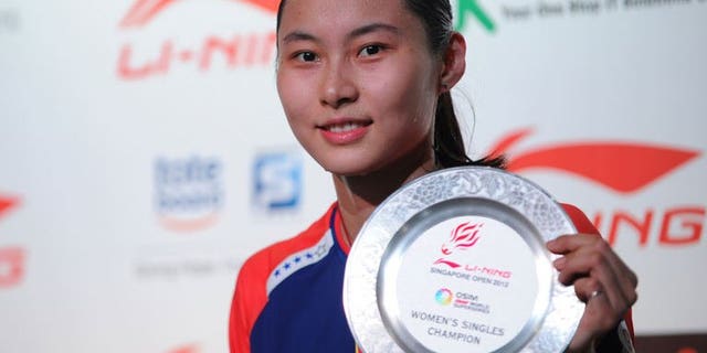 China's Wang Yihan poses with the plaque after winning against compatriot Li Xuerui during their women's singles final badminton match at the Singapore Open on June 23, 2013. Wang won 21-18, 21-12.
