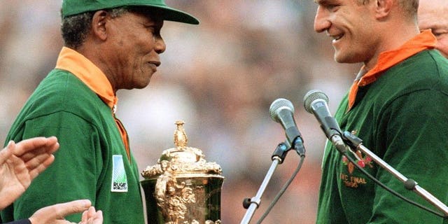 South Africa's then president Nelson Mandela (L) hands national rugby team captain Francois Pienaar the Webb Ellis Cup after South Africa won the 1995 Rugby World Cup final at Ellis Park Stadium, Johannesburg on June 24, 1995. With Mandela critically ill in hospital, South Africans on Monday recalled the day exactly 18 years ago when their team won the World Cup and Mandela won over the nation.