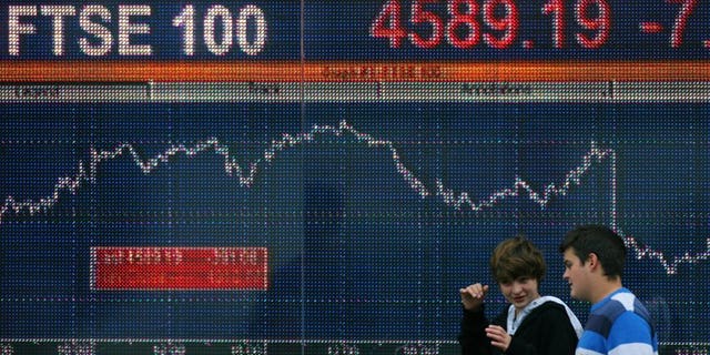 People walk past an electronic sign showing the level of the FTSE 100 in London in October 2008. London shares closed lower on Monday as stock markets fell across the world amid anxiety about a growing credit crunch in China, dealers said.