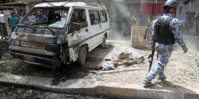 An Iraqi policeman walks past a damaged vehicle on the scene of a car bomb attack in Baghdad's commercial area of Karradah on May 30, 2013. A series of car bombs across Baghdad killed 15 people and wounded 65 on Monday, officials said, the latest in deadly violence that has sparked fears of a revival of full-blown sectarian war.