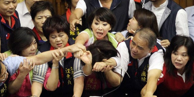 Legislators from Taiwan's ruling Kuomintang party and opposition try to seize the podium in parliament on June 25, 2013. Fighting broke out in Taiwan's parliament Tuesday as legislators scuffled and threw coffee during a debate on whether a controversial capital gains tax on share trading should be revised less than a year after it was brought in.