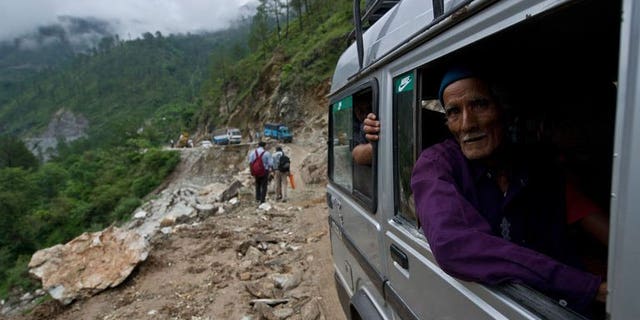 An elderly Indian man looks out as he drives past a damaged section of road between Rudraprayag and Gauchar, at Gauchar on June 25, 2013, after flash flooding hit the northern Indian state of Uttarakhand. An Indian television journalist reporting on the deadly floods that have swept northern India defended his decision on Tuesday to file a report while perched on a survivor's shoulders.