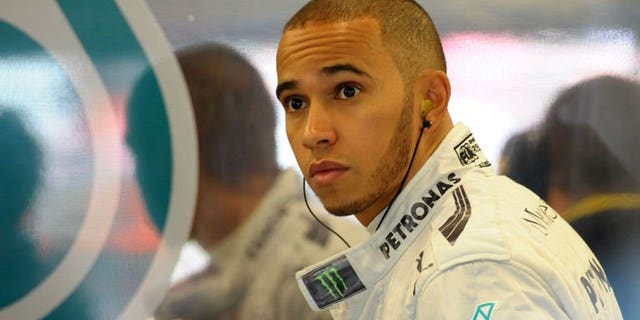 Mercedes' British driver Lewis Hamilton is reflected on a team logo in the pits during the first practice session at the Silverstone circuit on June 28, 2013. The Briton will start from pole position in British Grand Prix.