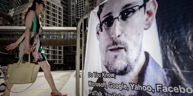 A woman walks past a banner displayed in support of former US spy Edward Snowden in Hong Kong on June 18, 2013. Four amateur filmmakers in Hong Kong have beaten Hollywood to the draw by producing the first film on Edward Snowden, a five-minute thriller depicting the nail-biting intrigue surrounding the intelligence leaker when he was hiding in the city.