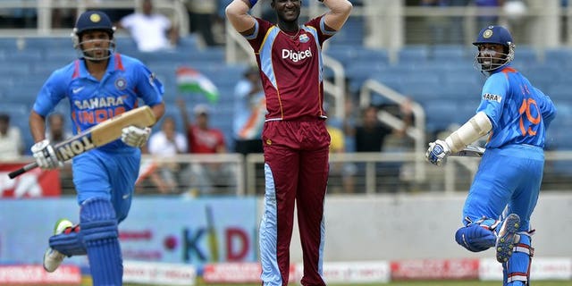 Dinesh Karthik (right) and Rohit Sharma take a run off the bowling of Darren Sammy (centre) in Kingston on Sunday. Stand-in West Indies captain Kieron Pollard won the toss and put India in to bat in the second match of the Tri-Nation One-Day International Series at Sabina Park.