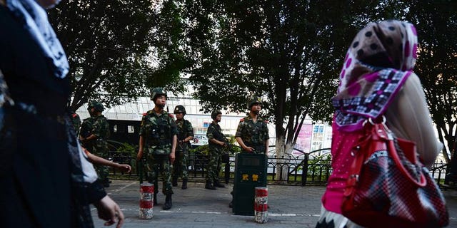 A woman walks by Chinese paramilitary police in Urumqi, Xinjiang, on June 30, 2013. Western media are encouraging "terrorism" in Xinjiang by misrepresenting violence in the region as ethnic conflict between minority Uighurs and Han Chinese, state-run media said.