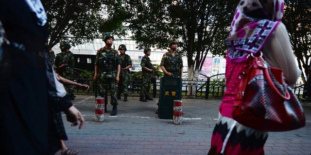 A woman walks by Chinese paramilitary police in Urumqi, Xinjiang, on June 30, 2013. Western media are encouraging "terrorism" in Xinjiang by misrepresenting violence in the region as ethnic conflict between minority Uighurs and Han Chinese, state-run media said.