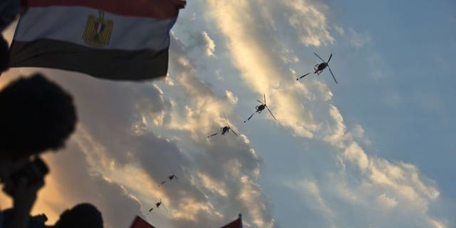 Egyptian army helicopters fly over as hundreds of thousands of Egyptian demonstrators gather outside the presidential palace in Cairo during a protest calling for the ouster of President Mohamed Morsi on July 1, 2013.