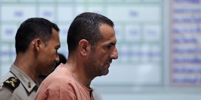 Lebanese-Swedish man Atris Hussein (centre) leaves a holding cell for the courtroom ahead of a scheduled hearing at a criminal court in Bangkok on June 11, 2013. Hussein on Tuesday denied links to the Hezbollah movement during his trial on charges of breaking Thailand's weapons laws.