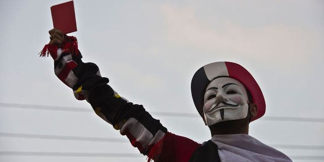 A protester wearing a Guy Fawkes mask holds up a red card as thousands of Egyptian demonstrators gather outside the presidential palace in Cairo, on July 1, 2013. US President Barack Obama has called President Mohamed Morsi to warn him that the voices of all Egyptians must be heard as a political crisis escalates, the White House said.