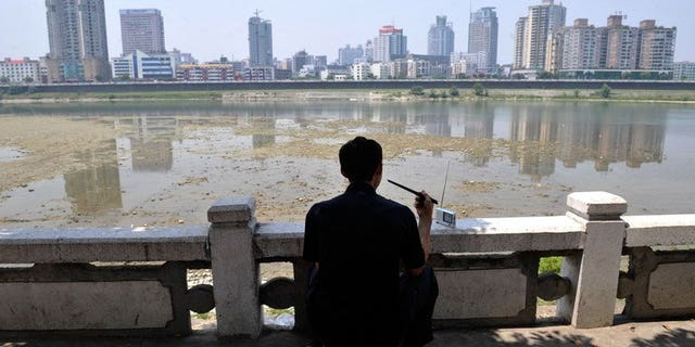 A man eats a meal as he listens to the radio in front of the Fujiang river in China's southwestern province of Sichuan on June 3, 2008. Several US legislators have urged Taiwan to stop tearing down shortwave radio transmission towers which have broadcast uncensored news to China since the 1960s.
