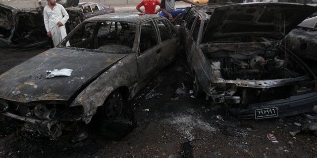 Iraqi men gather at the scene of a car bomb that exploded in Baghdad's Habibiyah area on May 27, 2013. A series of bombings minutes apart targeting markets across Baghdad have killed at least 15 people and wounded dozens of others, security and medical officials said.