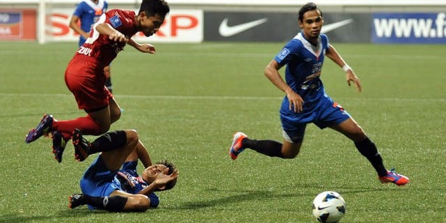 Singapore's LionsXII player Nazrul Nazari (L) leaps over KL Felda United player Mohd Akmal at the Jalan Besar Stadium during the Malaysian Super League in Singapore on July, 2 2013. The LionsXII clinched the Malaysian Super League title Tuesday with a clinical 4-0 win over minnows Felda United, rekindling the city-state's glory days in the competition after a nearly two-decade absence.
