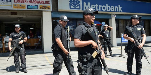 Members of the Pasay City SWAT team patrol in front of a bank in Manila on February 1, 2013. Five young men were shot dead before dawn on Wednesday in a street on the outskirts of the Philippines' main business district, police said.