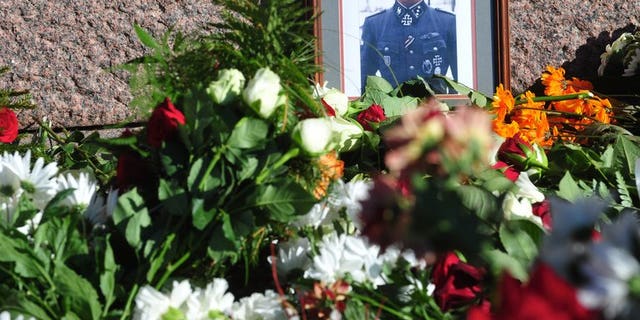 Flowers and a photo of a soldier wearing a uniform with Gestapo insignia and the Iron Cross are laid at the Monument of Freedom in Riga, Latvia where veterans of a force that was commanded by the German Nazi Waffen SS commemorated a key 1944 battle on March 16, 2013. The Simon Wiesenthal Centre Wednesday condemned plans by Latvian nationalists to mark a WWII event that led to a massacre of Jews.
