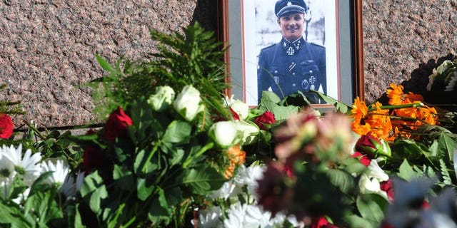 Flowers and a photo of a soldier wearing a uniform with Gestapo insignia and the Iron Cross are laid at the Monument of Freedom in Riga, Latvia where veterans of a force that was commanded by the German Nazi Waffen SS commemorated a key 1944 battle on March 16, 2013. The Simon Wiesenthal Centre Wednesday condemned plans by Latvian nationalists to mark a WWII event that led to a massacre of Jews.