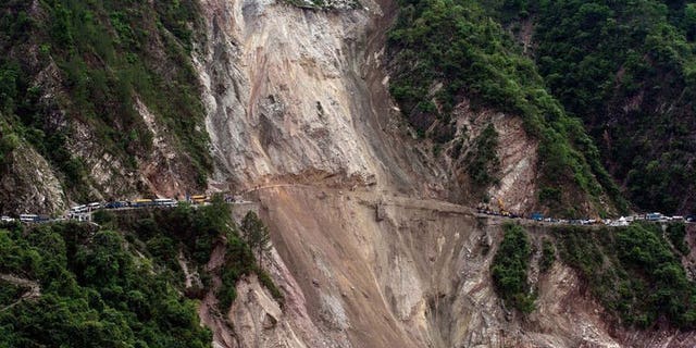 In this picture taken June 25, 2013, vehicles wait on the either side of a road -- linking Rudraprayag and Srinagar -- that was destroyed by a landslide in northern India. Landslides and floods triggered by several weeks of monsoon rains have killed at least 50 people in mainly remote parts of Nepal, a government official said Thursday.
