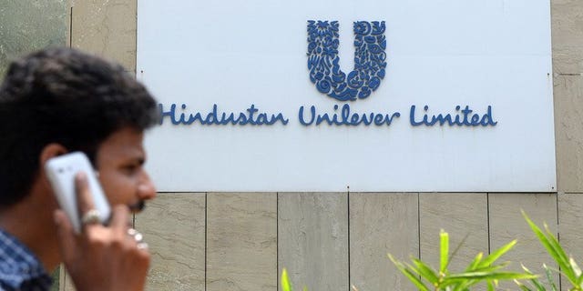 A pedestrian talks on his mobile phone as he walks past the offices of Hindustan Unilever Limited in Mumbai on April 30, 2013. Unilever said it has paid $3.2 billion for an additional 14.8 percent in its Indian subsidiary as part of its strategy of expanding in emerging markets.