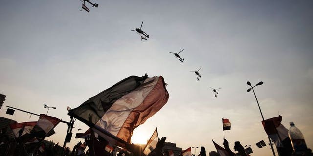 Egyptian people wave the national flag as army helicopters fly above Egypt's landmark Tahrir square on July 4, 2013. Egypt's controversial public prosecutor Abdel Meguid Mahmud said Friday he was to resign, days after being reinstated, citing possible conflicts of interest in future prosecutions.