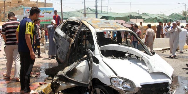 Iraqis inspect the site of a suicide car bomb attack in the Al-Haq square in Samarra, a predominantly Sunni town north of Baghdad, on July 5, 2013. Attacks killed eight people in town squares in Iraq on Friday, including seven who died when a suicide bomber dressed in army uniform set off his car rigged with explosives just before midday prayers.