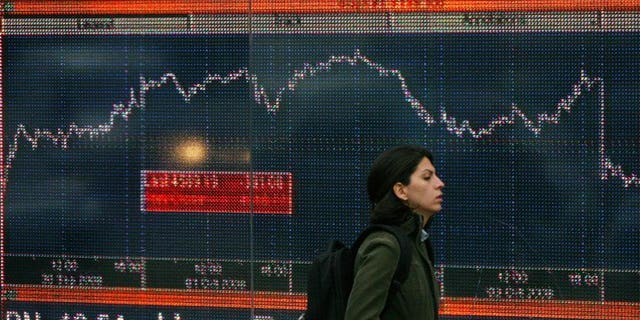 A woman walks past an electronic sign showing the FTSE 100 index in London in October 2008.