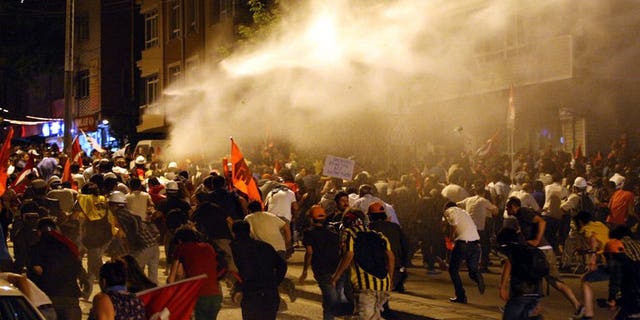 Protesters take cover from water cannon during clashes with police in Ankara on June 25, 2013. The Council of Europe's human rights commissioner Nils Muiznieks has urged an investigation into the use of excessive police force during a crackdown on anti-government protests in Turkey last month.