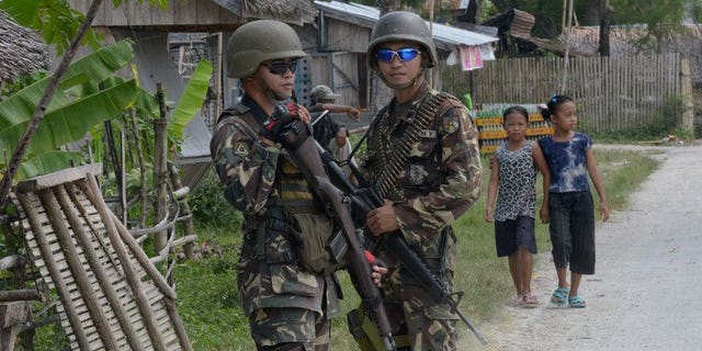 Soldiers guard a road in the Philippine town of Datu Salibo, on October 11, 2012. Communist insurgents have promised revenge after Philippine soldiers killed their regional spokesmen along with seven other rebels in the latest operation against the militants since talks to end one of Asia's longest running insurgencies collapsed.