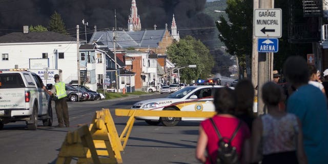 Residents watch rising smoke after a freight train loaded with oil derailed in Lac-Megantic in Canada's Quebec province on June 6, 2013. At least 80 people are missing in the small Canadian town after the accident, a firefighter told AFP.
