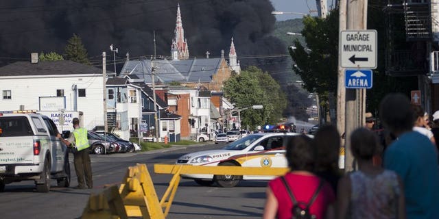 Residents watch rising smoke after a freight train loaded with oil derailed in Lac-Megantic in Canada's Quebec province on June 6, 2013. At least 80 people are missing in the small Canadian town after the accident, a firefighter told AFP.