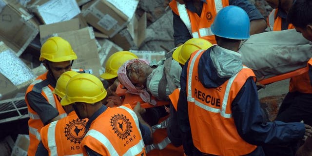 Rescue personnel move an injured worker from the rubble of a collapsed building in Mumbai on July 4, 2013. A two-storey hotel collapsed in the southern Indian city of Secunderabad, killing five restaurant workers and injuring 15 others.