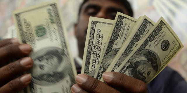 An Indian man counts US dollar notes at a currency exchange shop in Mumbai on June 26, 2013. India's rupee fell to a new record low against the dollar, as the greenback was boosted by another set of strong US economic data.