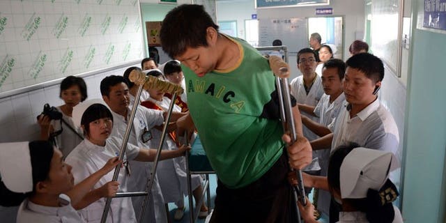 Wang Fengjun gets off a specially designed chair at a hospital in Zhengzhou, central China, on July 6, 2013. Wang, who is among the world's tallest living people, has been hospitalised for a hip replacement.