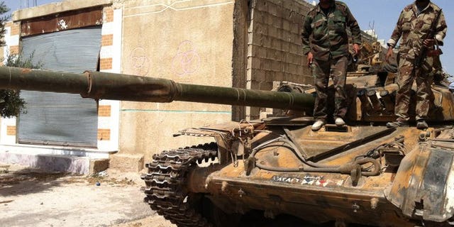 Syrian army soldiers stand on a tank in the village of Buweida, in Homs province on June 8, 2013. Syrian troops have advanced into the rebel-held Khaldiyeh district of central Homs, with shelling intensifying as forces battled for a 10th day in the area, activists and an NGO said.
