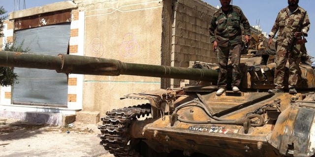Syrian army soldiers stand on a tank in the village of Buweida, in Homs province on June 8, 2013. Syrian troops have advanced into the rebel-held Khaldiyeh district of central Homs, with shelling intensifying as forces battled for a 10th day in the area, activists and an NGO said.