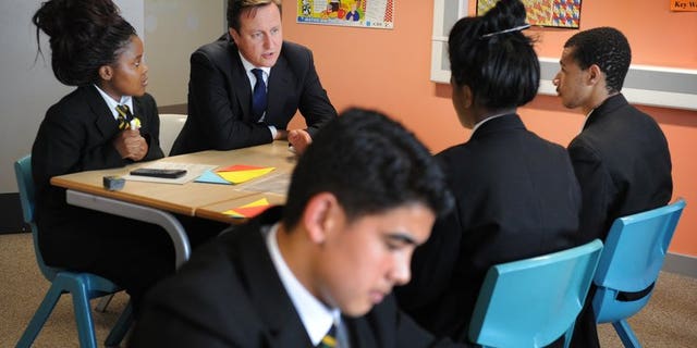 British Prime Minister David Cameron (second left) speaks to students in a mathematics class at Cedar Mount high school in Gorton, Manchester on October 4, 2011. Children will learn to write computer programmes and study internet safety from their first two years of school under a revised national curriculum unveiled Monday.