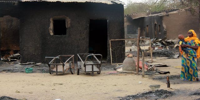 A woman stands near her burnt house in Nigeria's remote northeast town of Baga on April 21, 2013 after two days of clashes between officers and members of the Nigerian-based Islamist extremist group Boko Haram. The group is to be banned in Britain under anti-terror laws, the British interior ministry announced on Monday.